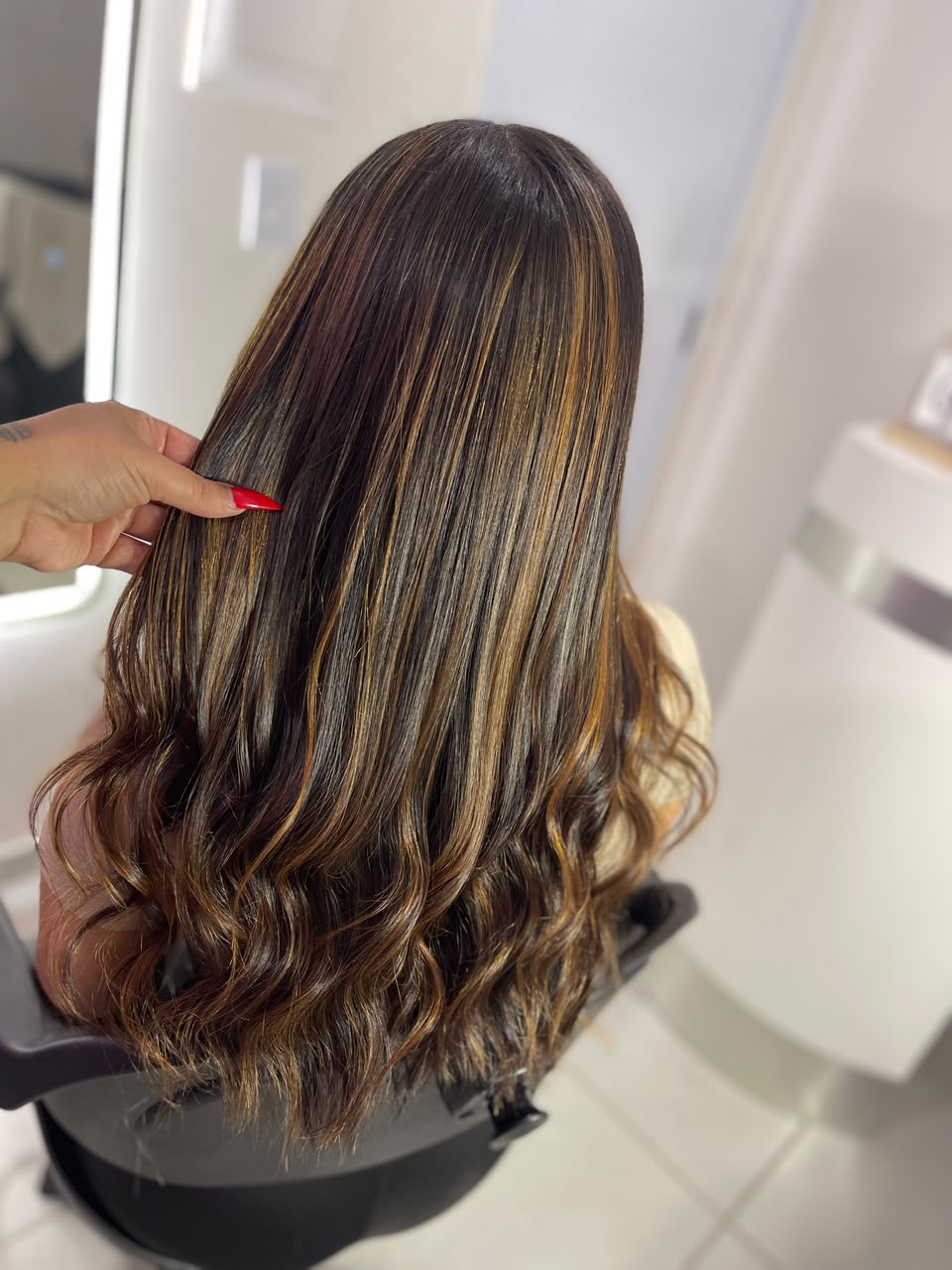 Cabelo castanho com mechas caramelo finalizado com ondas